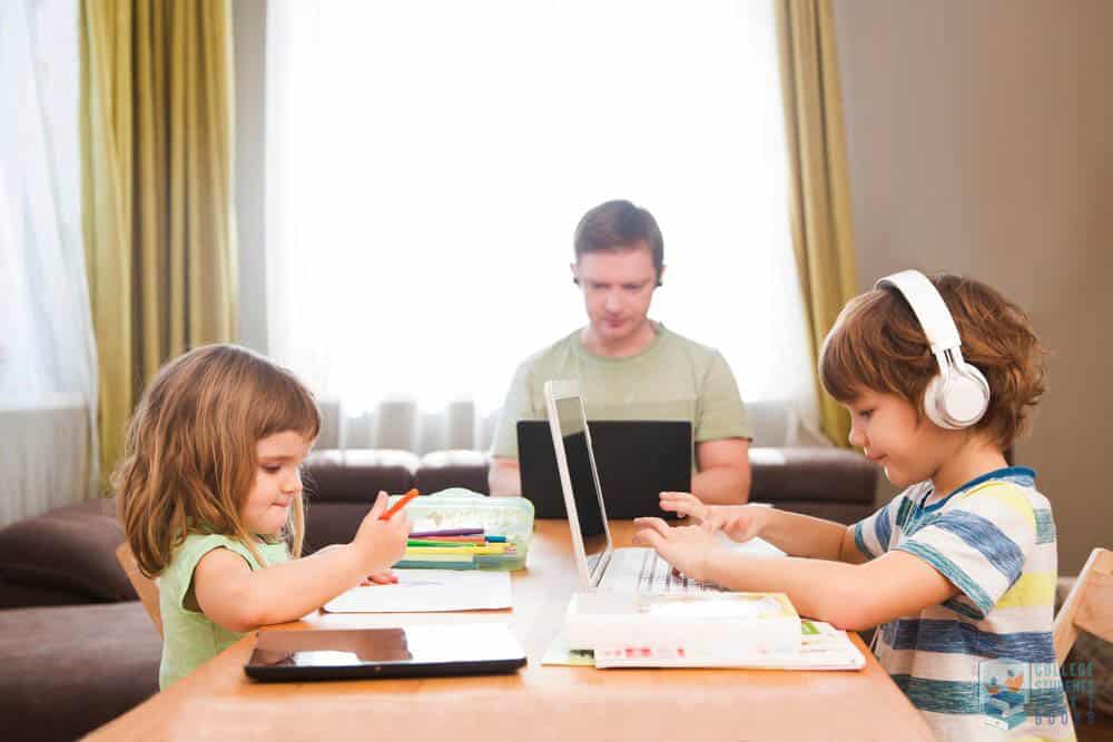 Embrace EdTech - 2 children sitting in front of each other, using technology to learn while their dad is using a laptop